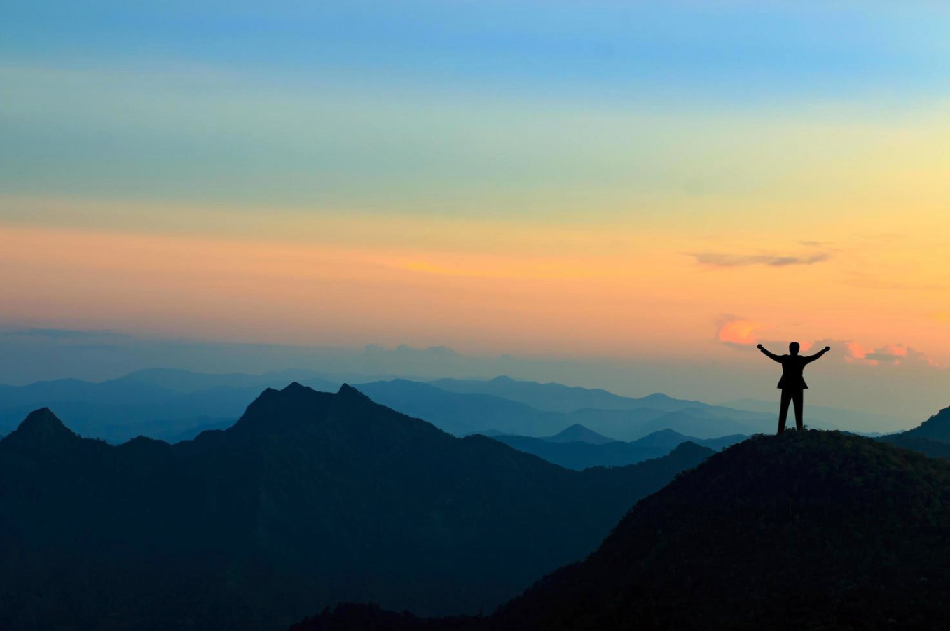 Person celebrating success from a mountain peak